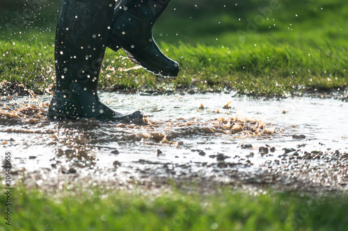 Φωτογραφία person in boots having fun in a large wet muddy puddles