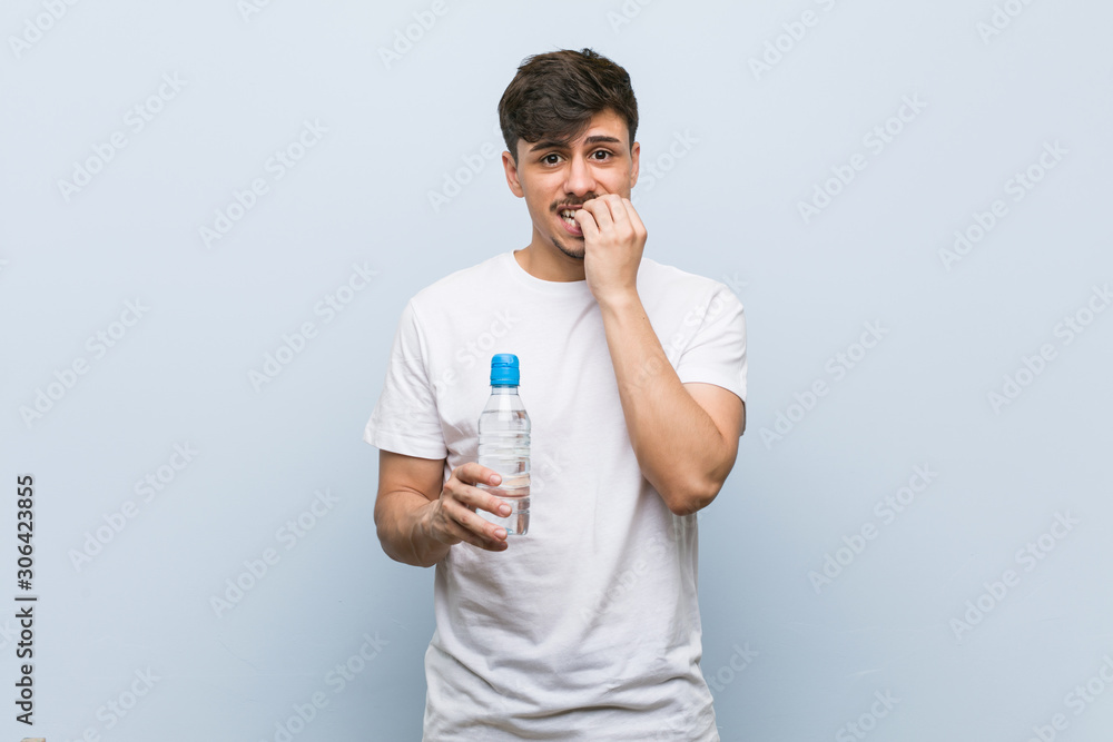Young hispanic man holding a water bottle biting fingernails, nervous and very anxious. Young hispanic man holding a water bottle biting fingernails, nervous and very anxious.