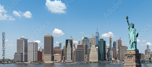 The Statue of Liberty over the panoramic view of lower manhattan skyline of New York city.