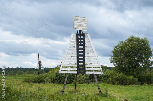 Two navigation signs marking the ship's course on the riverside. Wooden signal boards consist of square and trapezoid and are painted white with a black stripe in the middle
