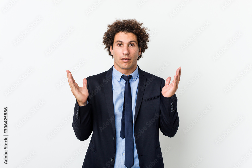 Young business curly man against white background surprised and shocked. Young business curly man against white background surprised and shocked.