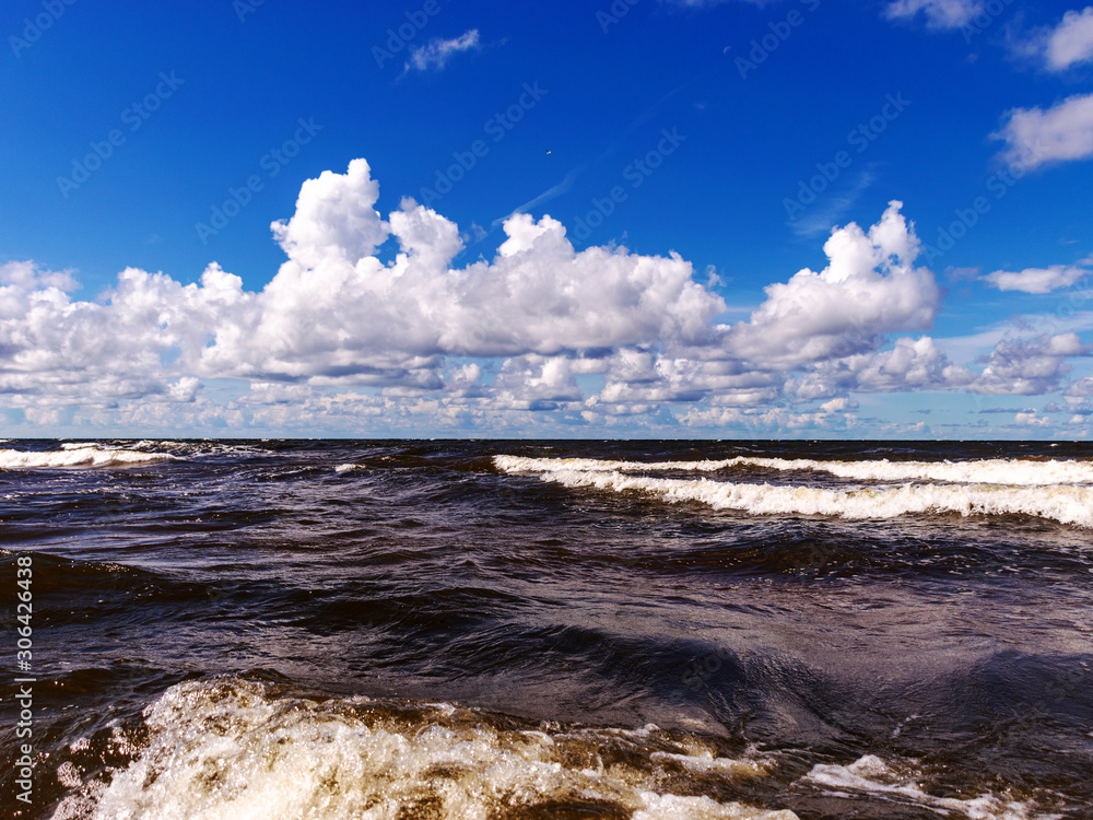 blurred foreground with sparkling waves, clouds and sea in the background