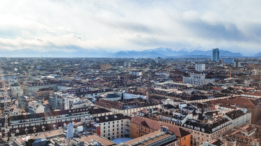 Panoramic aerial top view cityscape of Turin in Italy; Overlooking historical buildings and landmarks with snow capped mountains in the background. 