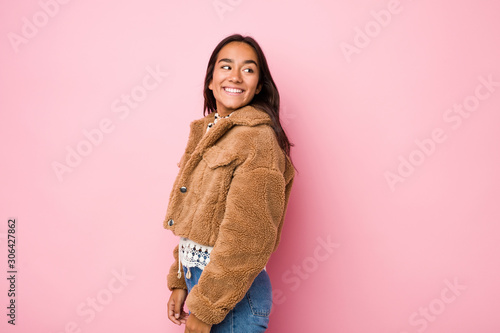 Young mixed race indian woman wearing a short sheepskin coatlooks aside smiling, cheerful and pleasant. © Asier
