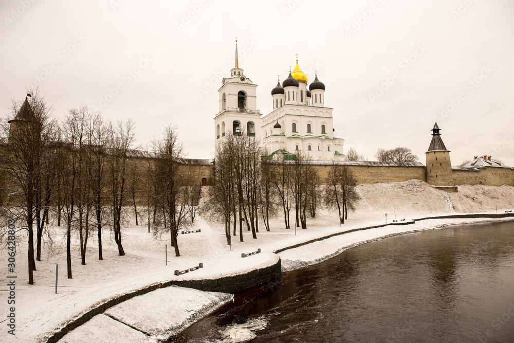 The old medieval fortress is covered with freshly fallen snow. Above the old walls rises the Cathedral and the bell tower. Pskov, Russia.