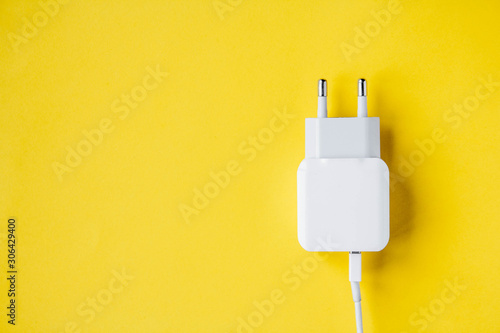 Mobile charger and USB Cable on yellow background. Top view. Copy, empty space for text