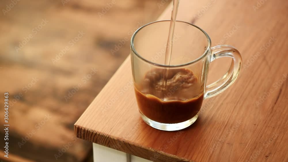Making instant coffee. Slow motion water pouring into glass cup with instant coffee granules Making instant coffee. Slow motion water pouring into glass cup with instant coffee granules