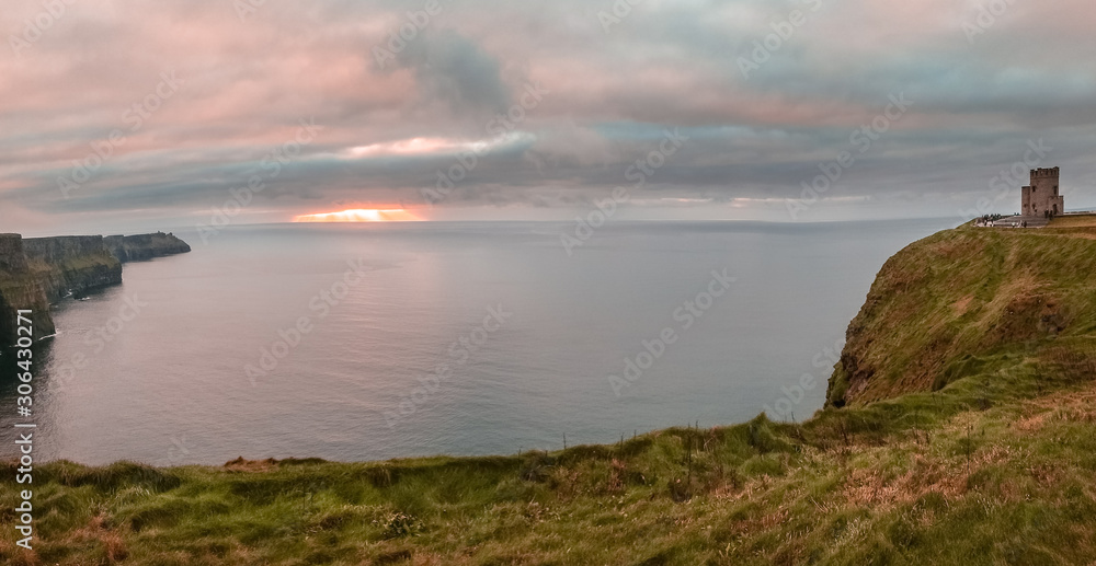 Cliffs of Moher, Ireland - panoramic view at sunset over sea cliffs next to O'Brien's Tower located at the southwest of the Burren region in County Clare.