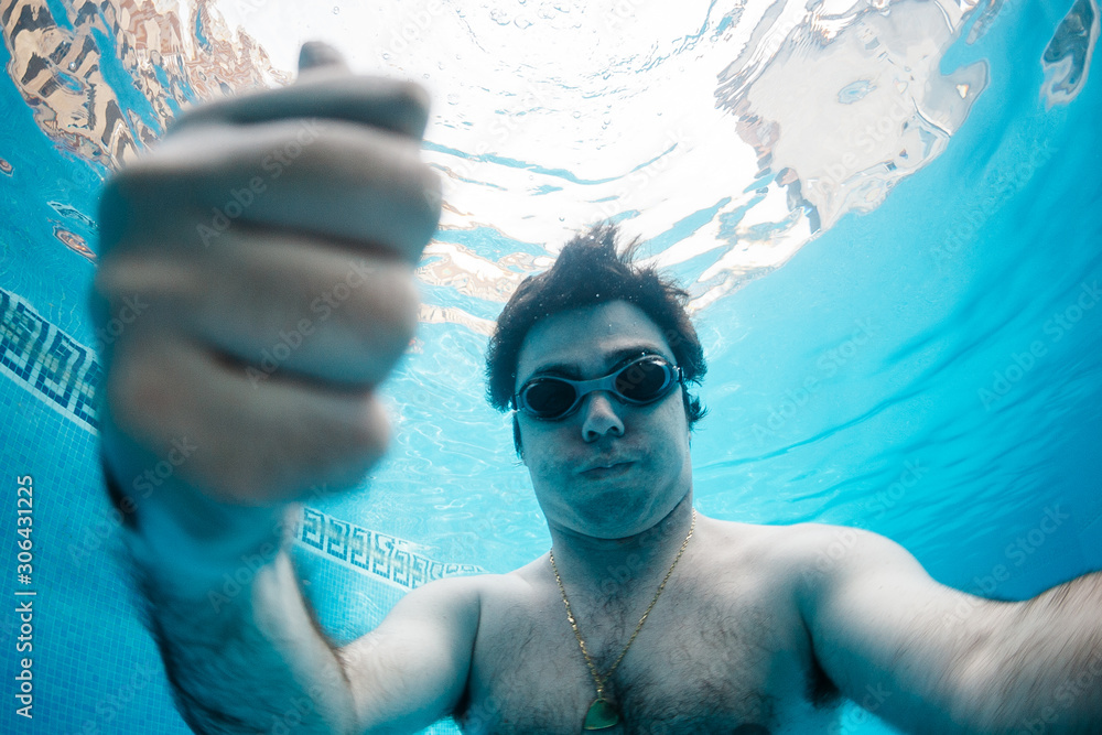Hombre con gafas de natación buceando en piscina