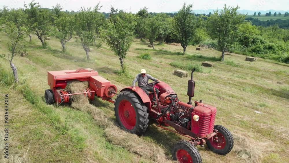 Aerial of a farmer with a tractor carrying a hay baler through a field Aerial of a farmer with a tractor carrying a hay baler through a field