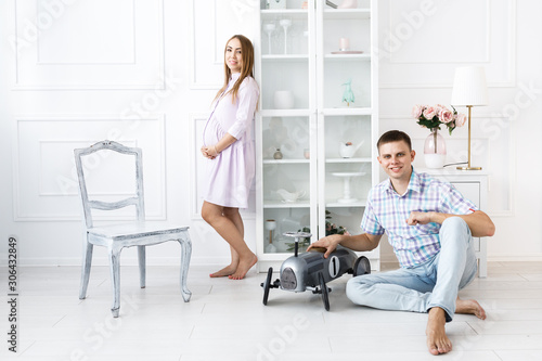 A man and a pregnant woman spend time together and sit on the floor.Beautiful bright guest room