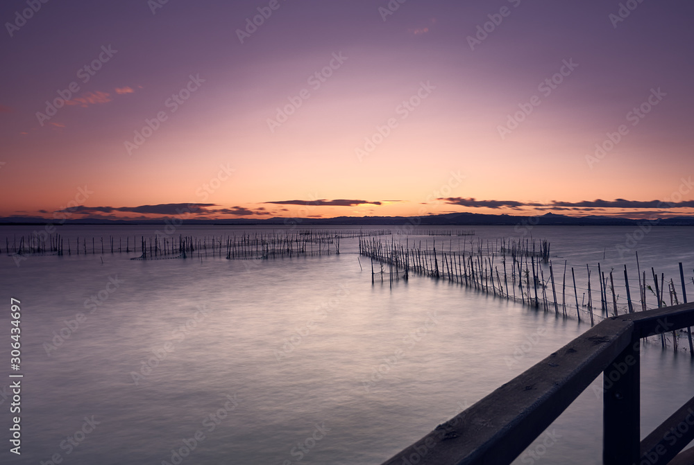 Sunset landscape on a lake with a railing in the foreground