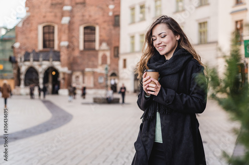 Female hand with paper cup of coffee take away. Woman holding cup on the urban background