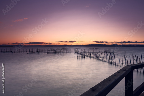 Sunset landscape on a lake with a railing in the foreground © daniel