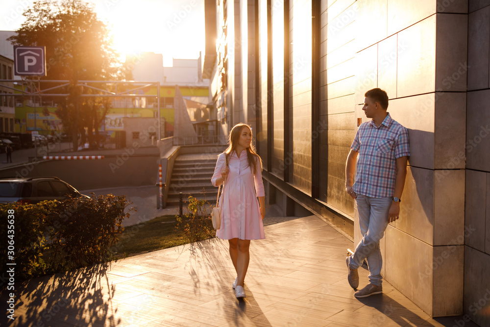 Young couple - man and woman expecting a baby, spend time together on the city street at sunset. Young couple - man and woman expecting a baby, spend time together on the city street at sunset.