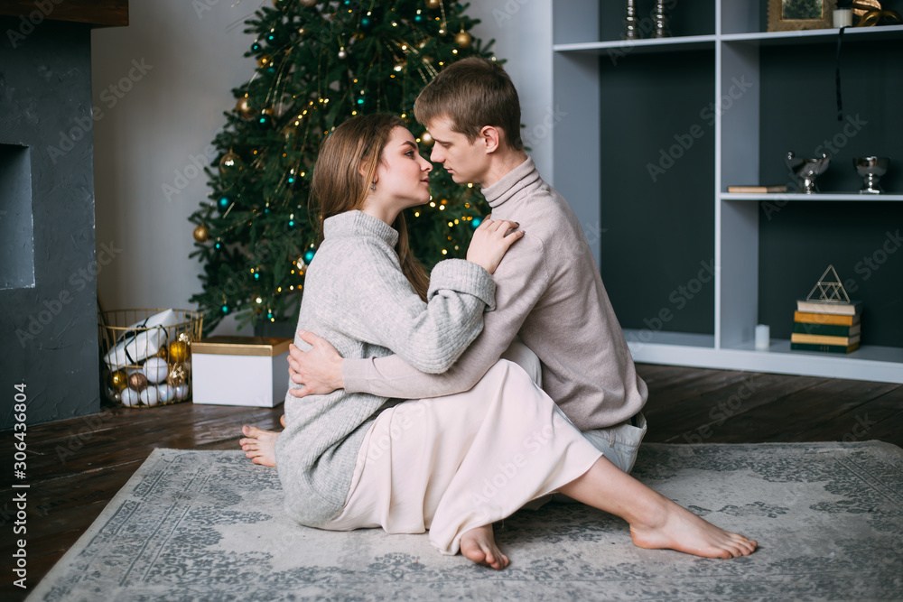 young man and woman hugging over Christmas tree