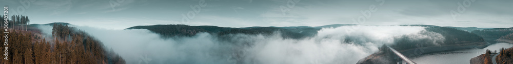 Moody dark and cold winter vibes with heavy fog in the nature mountains with autumn trees silhouettes. Moody dark and cold winter vibes with heavy fog in the nature mountains with autumn trees silhouettes.