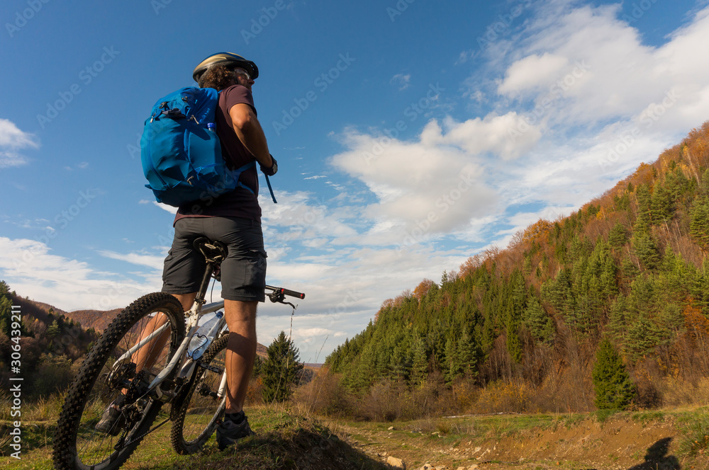 Mountain biker riding bike in the forest on dirt road. Mountain biker rides in autumn forest. Cycle trail in autumn forest. Mountain biking in autumn landscape forest