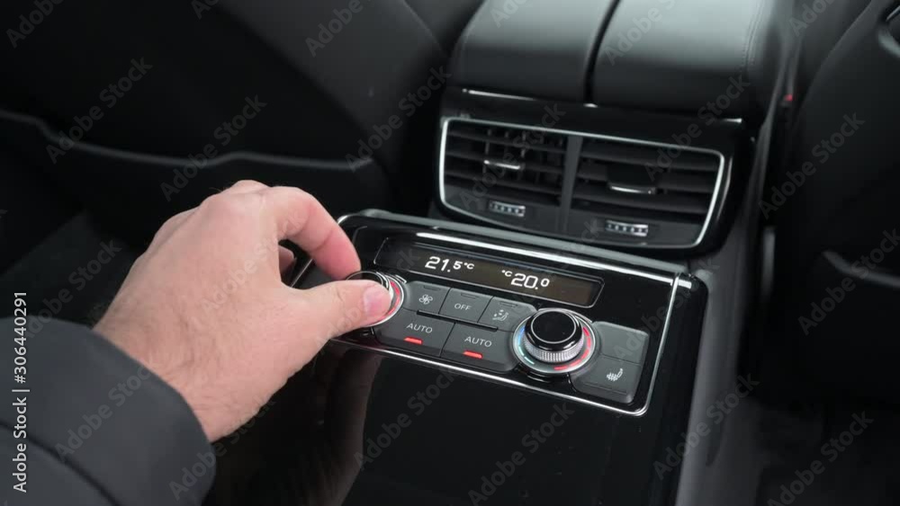 Hand adjusting climate control in the rear of a luxury vehicle Hand adjusting climate control in the rear of a luxury vehicle