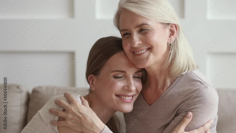 Happy mature mother embracing young daughter enjoy moments of tenderness Happy mature mother embracing young daughter enjoy moments of tenderness