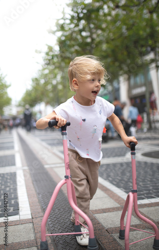 A little girl with a disability walks through the city with prostheses.