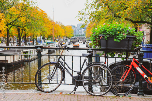 Bicycles on a bridge over the canals of Amsterdam. Colorful houses and flowers. Autumn.