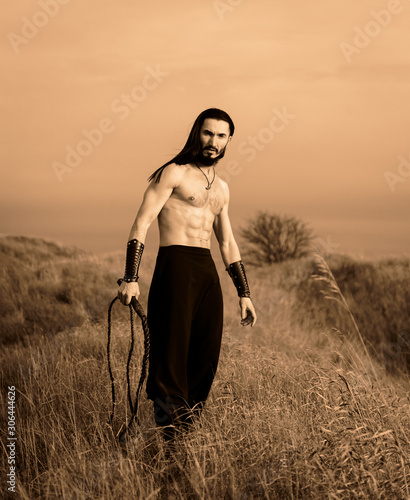 Young ukrainian man with long hair at the open steppe in Ukraine historical costume photo