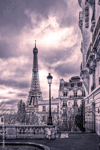 Paris, France - November 24, 2019: Small paris street with view on the famous paris eiffel tower on a cloudy day with some sunshine © JEROME LABOUYRIE