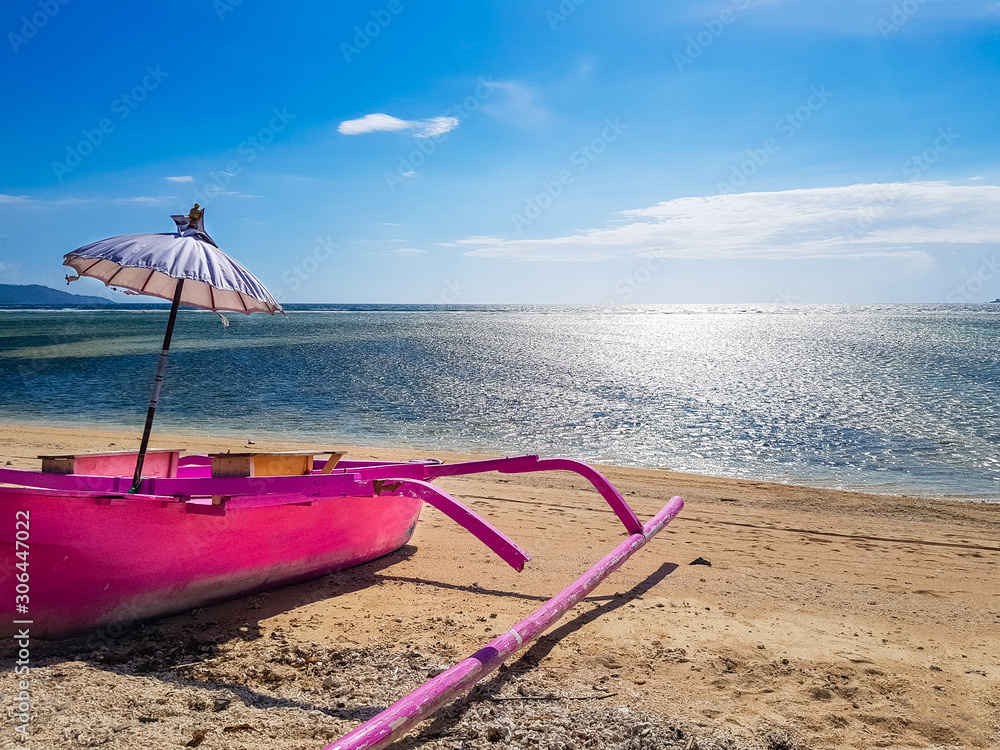 Gili Air, Lombok, Indonesia - Pink boat on the beach with umbrella next to wooden water swing in the Gili islands. Popular instagram location and holiday destination in Indonesia. Gili Air, Lombok, Indonesia - Pink boat on the beach with umbrella next to wooden water swing in the Gili islands. Popular instagram location and holiday destination in Indonesia.