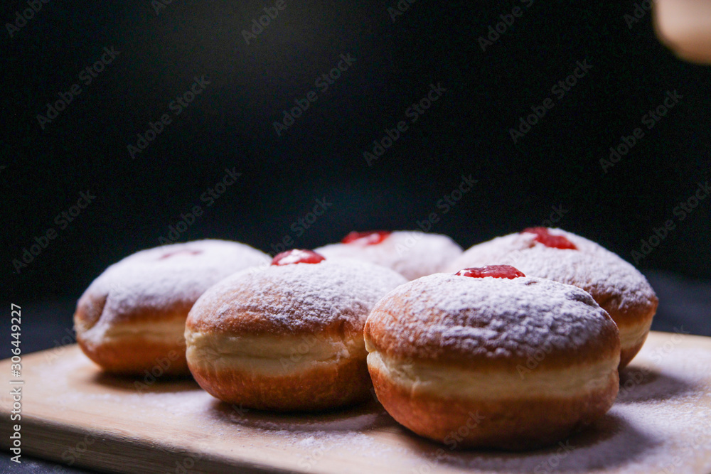 Hanukkah food doughnuts with jelly and sugar powder on black background. Jewish holiday Hanukkah concept and background. Copy space for text. Shallow DOF Hanukkah food doughnuts with jelly and sugar powder on black background. Jewish holiday Hanukkah concept and background. Copy space for text. Shallow DOF