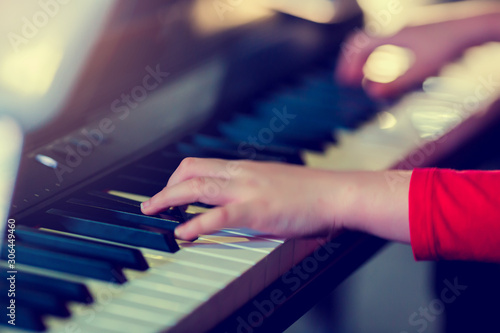 Closeup kid's hand playing piano on stage with lighting. Favorite classical music. There are musical instrument for concert or learning music. The concept of musical instrument.