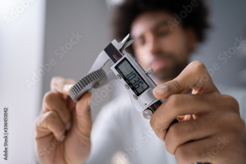 Man Measuring Gear's Size With Digital Caliper photo