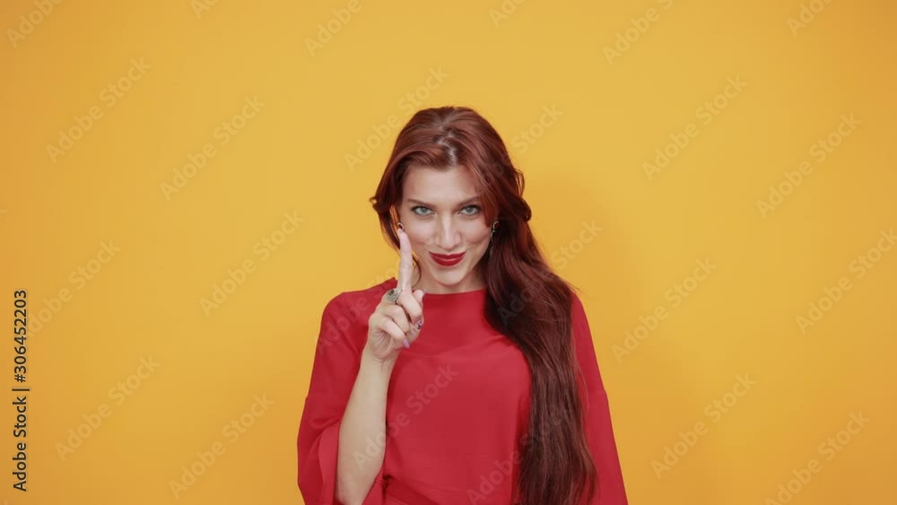 Teenager caucasian woman wearing fashion red shirt over orange wall background making phone gesture and doubting Teenager caucasian woman wearing fashion red shirt over orange wall background making phone gesture and doubting