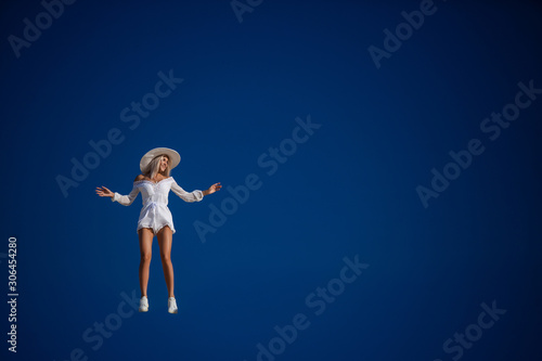 cheerful girl jumping against the blue sky