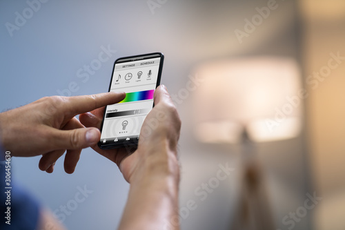 Human Hand Adjusting Electric Light Through Mobile Phone