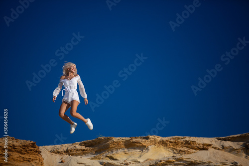 attractive girl jumping on the beach against the blue sky
