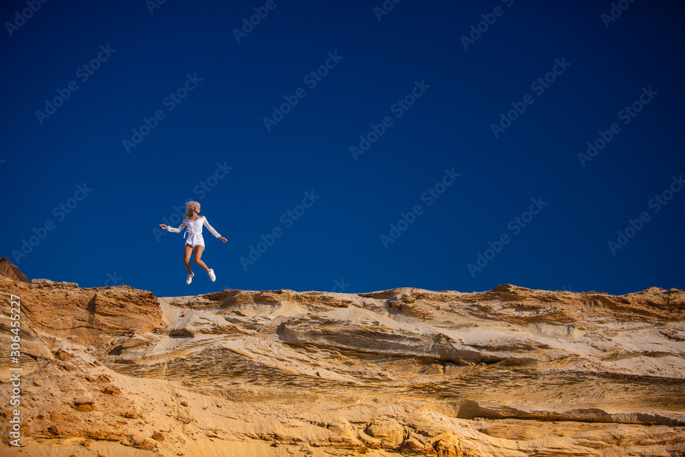 attractive girl jumping on the beach against the blue sky