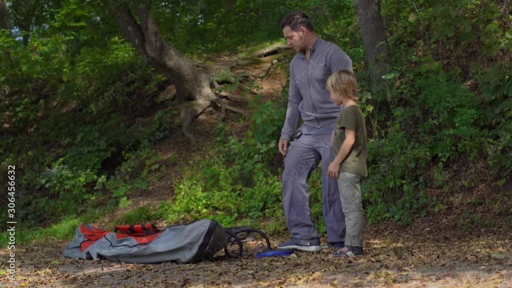 A young man and his little son on a lake or seaside prepare a big inflatable kayak for swimming A young man and his little son on a lake or seaside prepare a big inflatable kayak for swimming