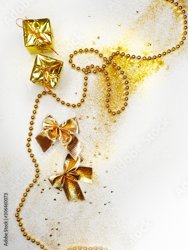 Festive new-year flat lay. Gold decor on white background. Sparkling holiday bows beads and gift boxes