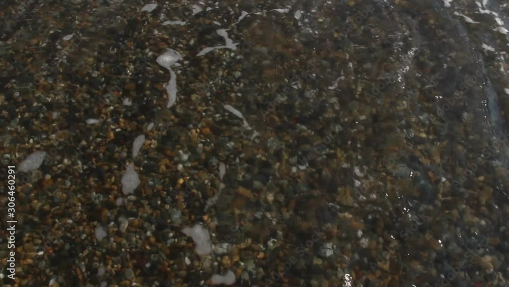sea waves on a pebble beach, water foams sea waves on a pebble beach, water foams