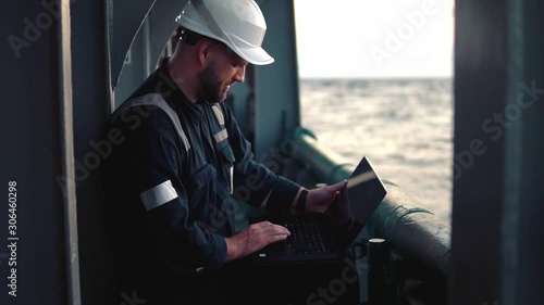 Marine chief officer or captain on deck of vessel or ship watching laptop. Internet and home connection at sea. photo