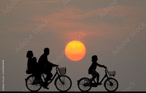 silhouette happy family ride bike on sunrise