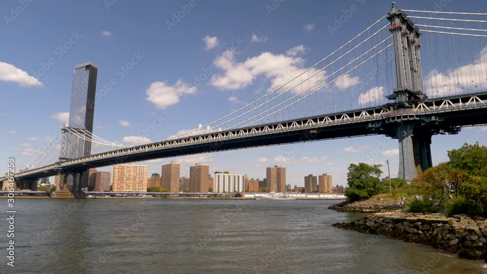 Width of East River spanning like the Manhattan Bridge from Brooklyn to NYC w/ skyline and skies