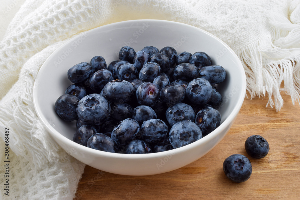 Bowl of fresh organic blueberries on rustic wooden table draped Bowl of fresh organic blueberries on rustic wooden table draped