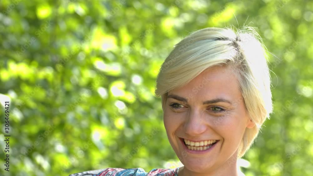Happy, blonde woman, smiling with green lush background Happy, blonde woman, smiling with green lush background
