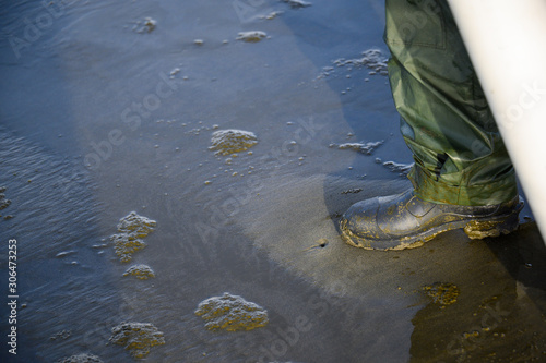 Valokuva Rubber booted foot testing clam dimple in sand for razor clam, Ocean Shores, Was