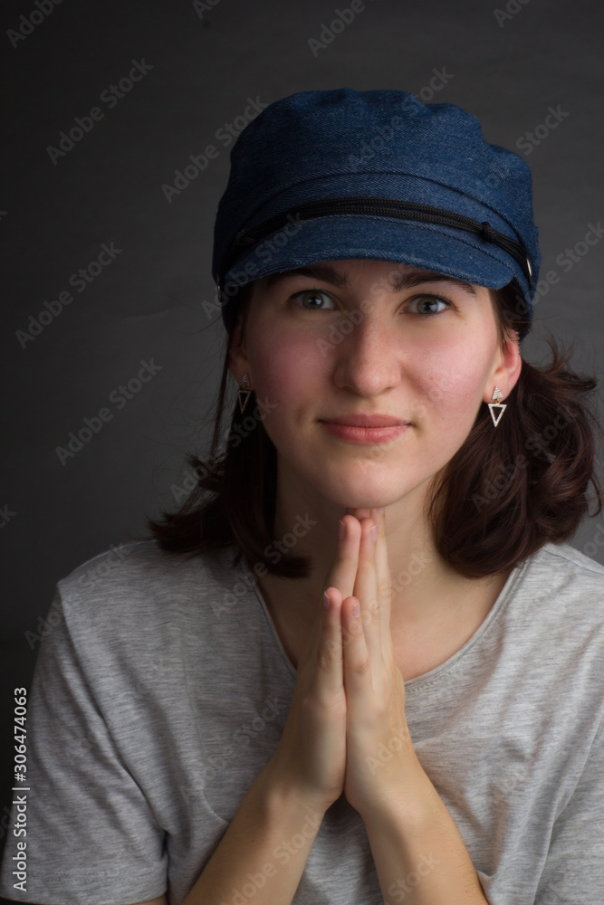 portrait of a brunette in a gray t-shirt and blue denim cap