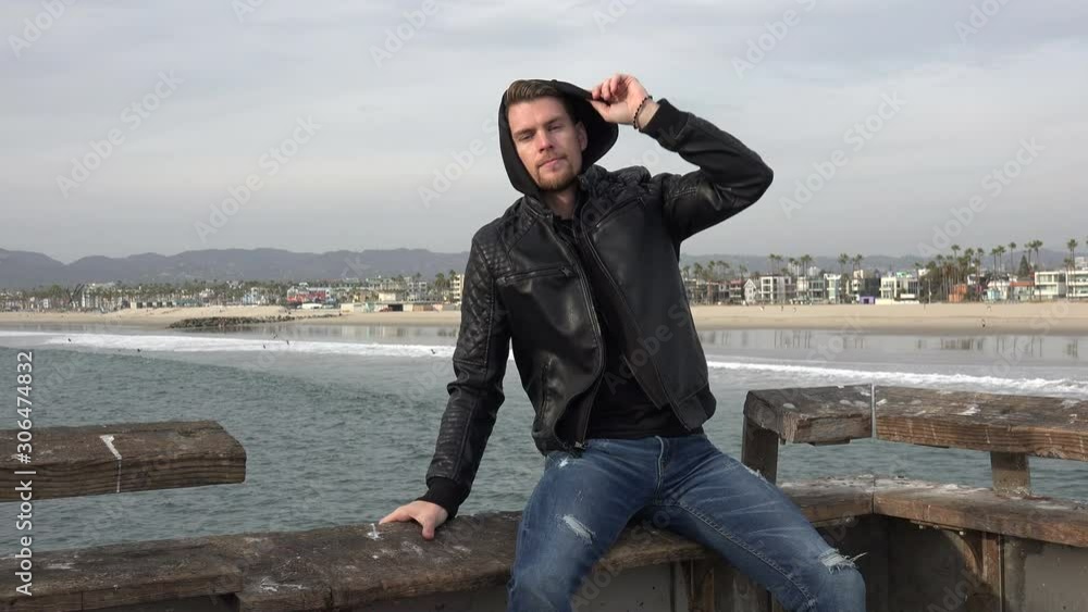 Stylish young man sitting on a pier by the ocean Stylish young man sitting on a pier by the ocean