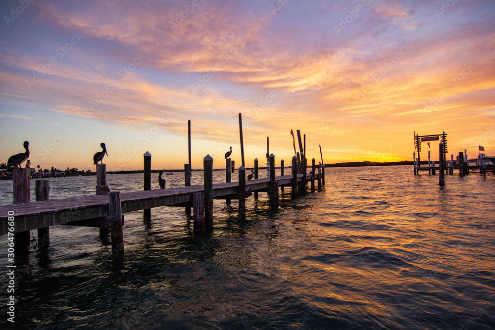 Colorful Sunrise on Old Wooden Dock with Flock of Pelicans and Choppy Waves