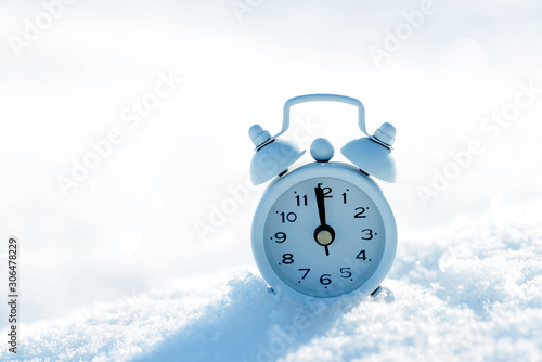 Small alarm clock in snow with copy space for your text.